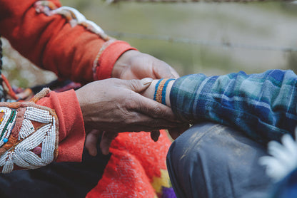 Artisan tying a handmade bracelet on the wrist of a traveler